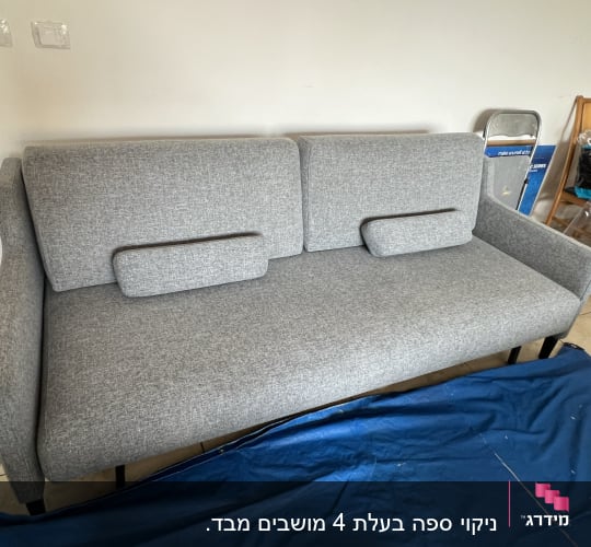ספה אפורה עם כיסוי כחול על הרצפה